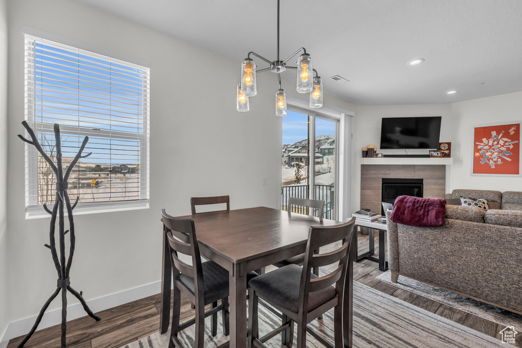 Dining area with wood finished floors, baseboards, recessed lighting, and a tiled fireplace