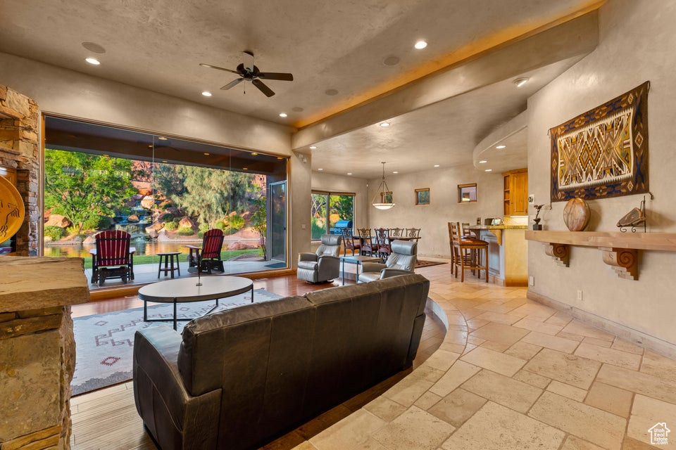 Living room with recessed lighting, a ceiling fan, plenty of natural light, and stone tile floors