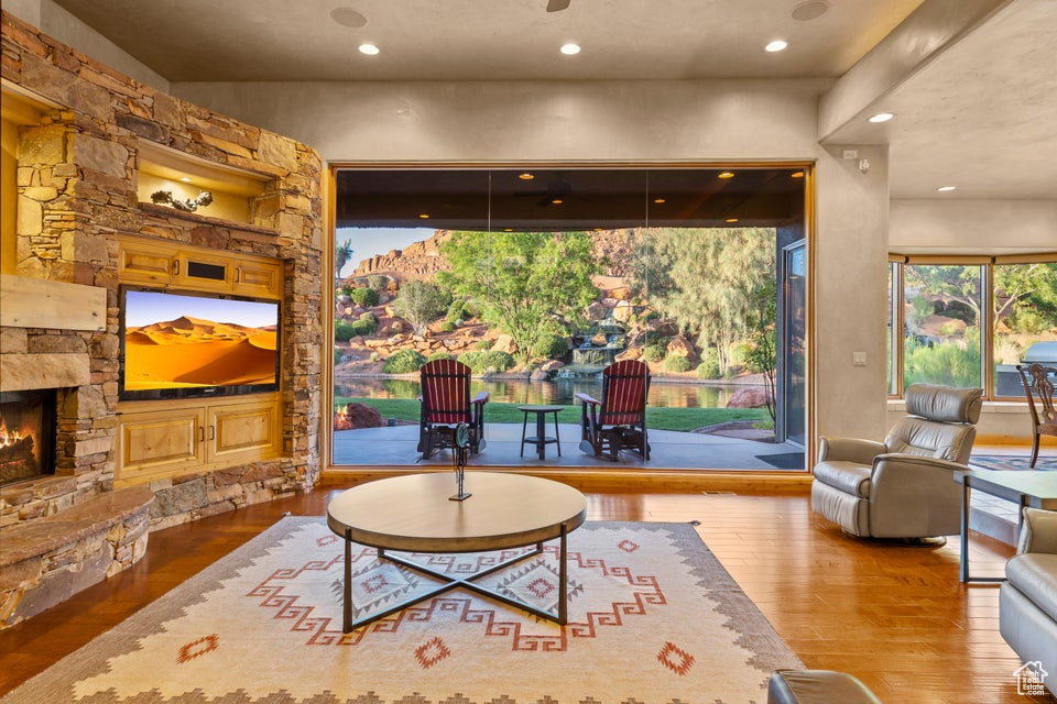 Living area featuring wood-type flooring, a stone fireplace, and recessed lighting