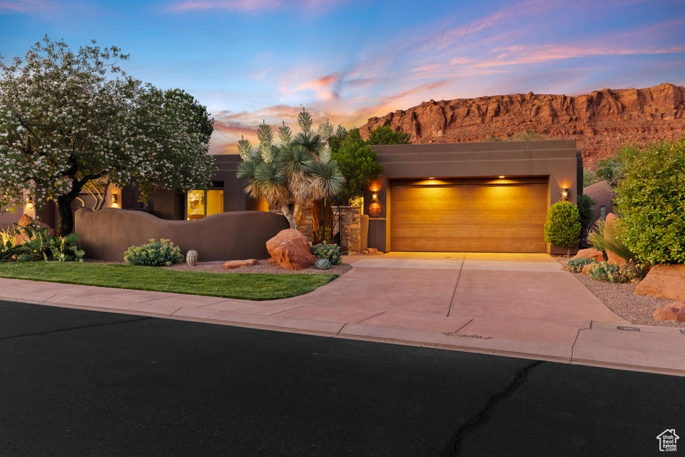 Pueblo revival-style home featuring driveway, a garage, a mountain view, and stucco siding