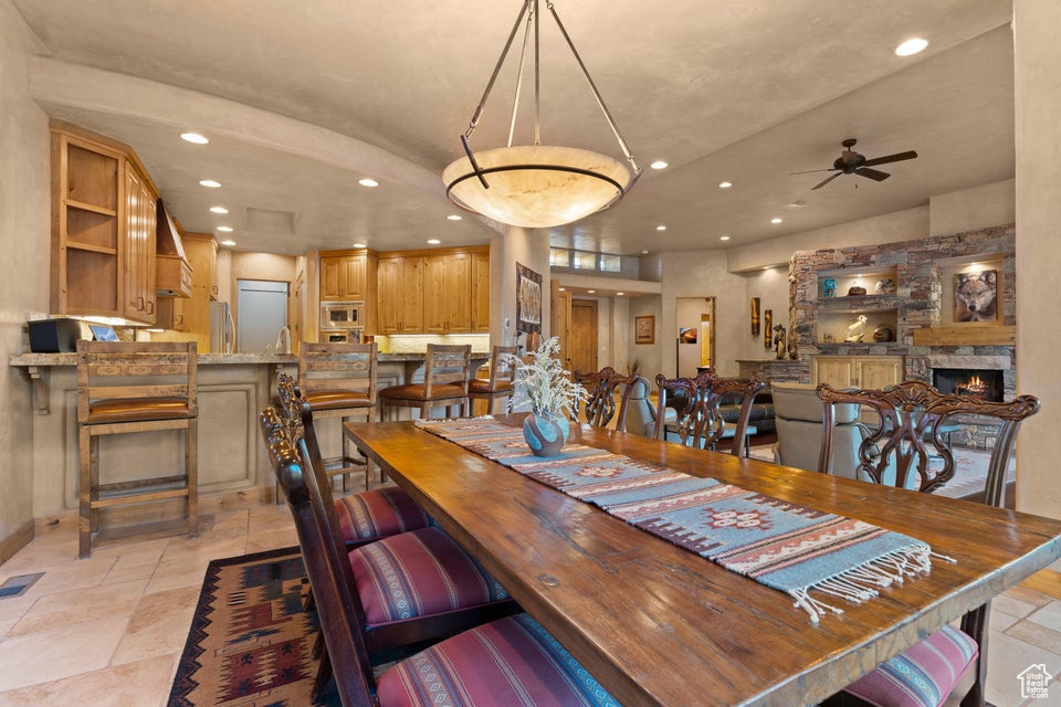 Dining area with recessed lighting, a ceiling fan, baseboards, and a stone fireplace