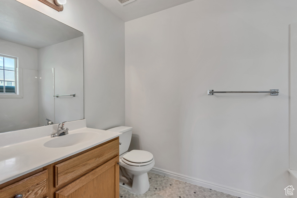 Bathroom with toilet, vanity, and baseboards
