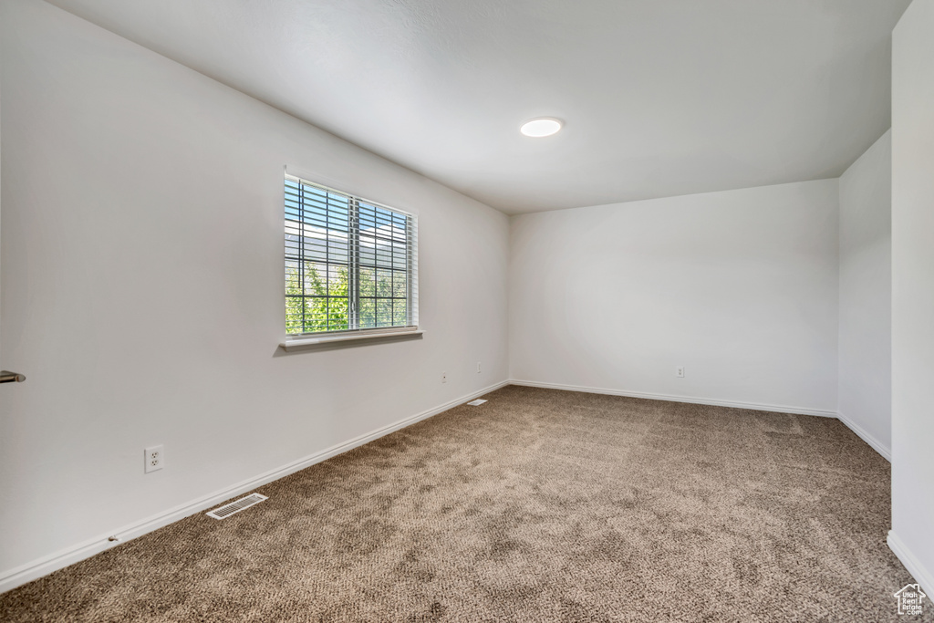 Carpeted spare room featuring baseboards