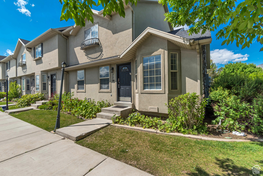 Townhome / multi-family property featuring stucco siding and a front yard