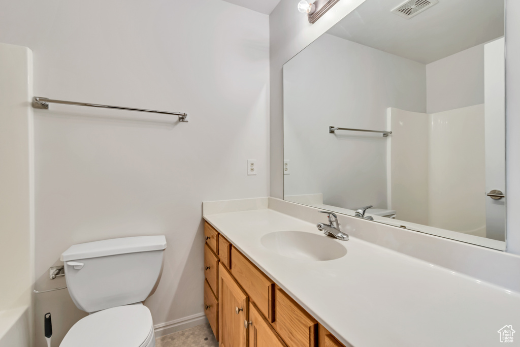 Bathroom featuring toilet, vanity, and baseboards