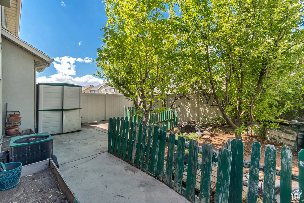 Fenced backyard with central AC unit and a patio area