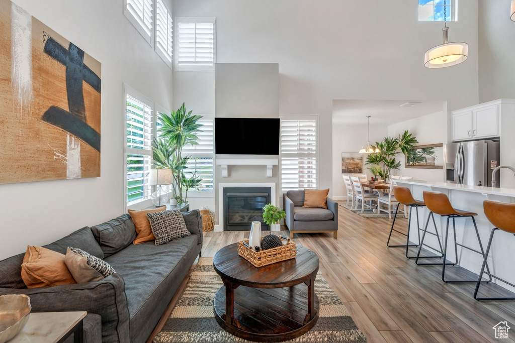 Living area with a towering ceiling, light wood-style floors, and a glass covered fireplace