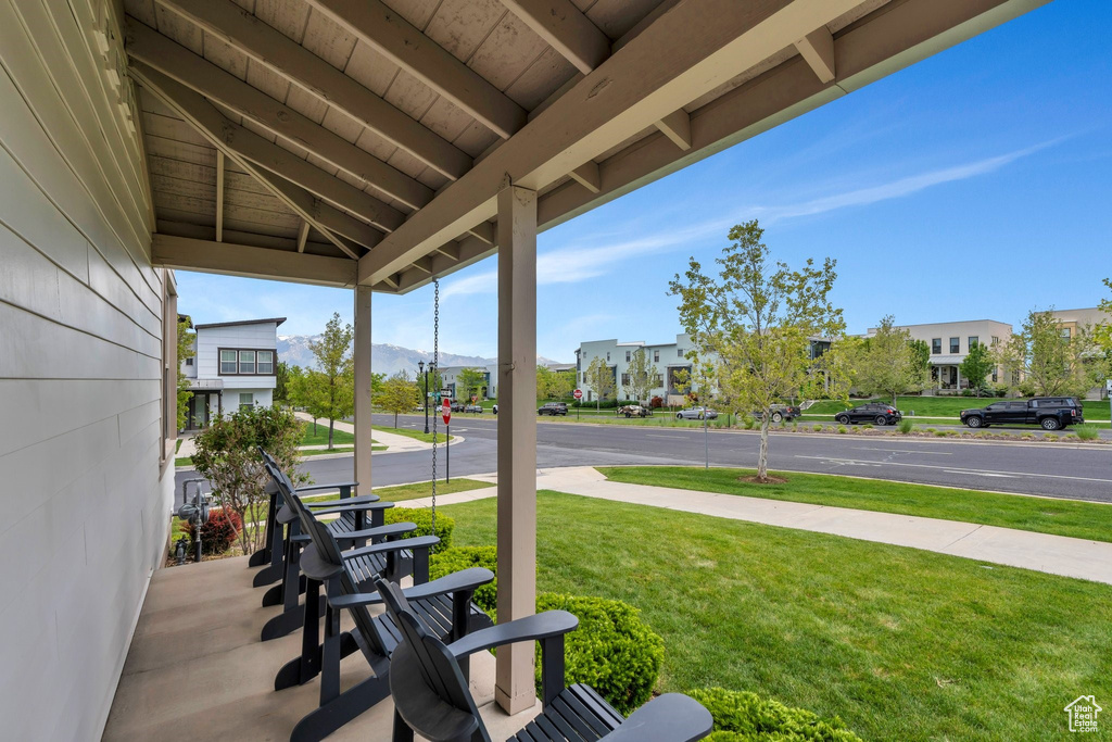 Covered porch with a mountain view and a lawn