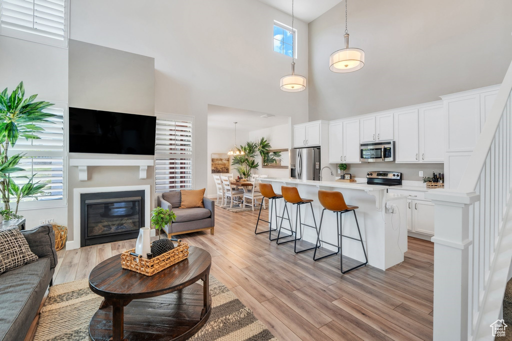 Kitchen featuring appliances with stainless steel finishes, open floor plan, a high ceiling, a glass covered fireplace, and a breakfast bar