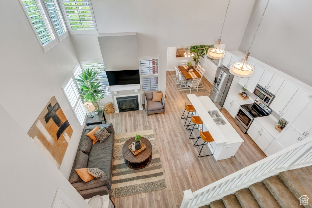 Living area featuring a towering ceiling, light wood finished floors, and a glass covered fireplace