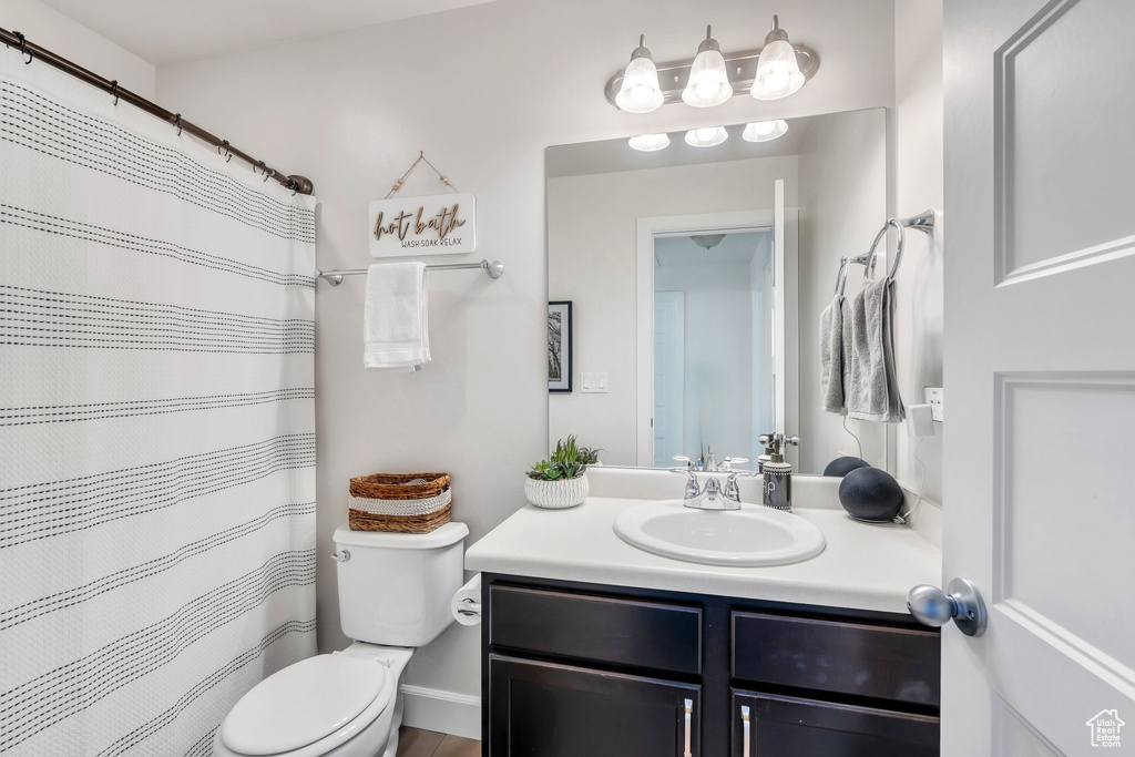 Bathroom with toilet, vanity, and curtained shower