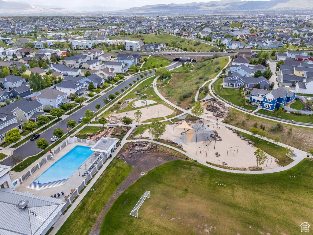 Aerial view of property and surrounding area with a pool, mountains, and nearby suburban area