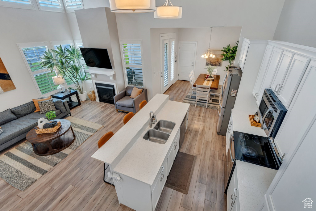 Living area featuring a fireplace, light wood-style floors, healthy amount of natural light, and a high ceiling