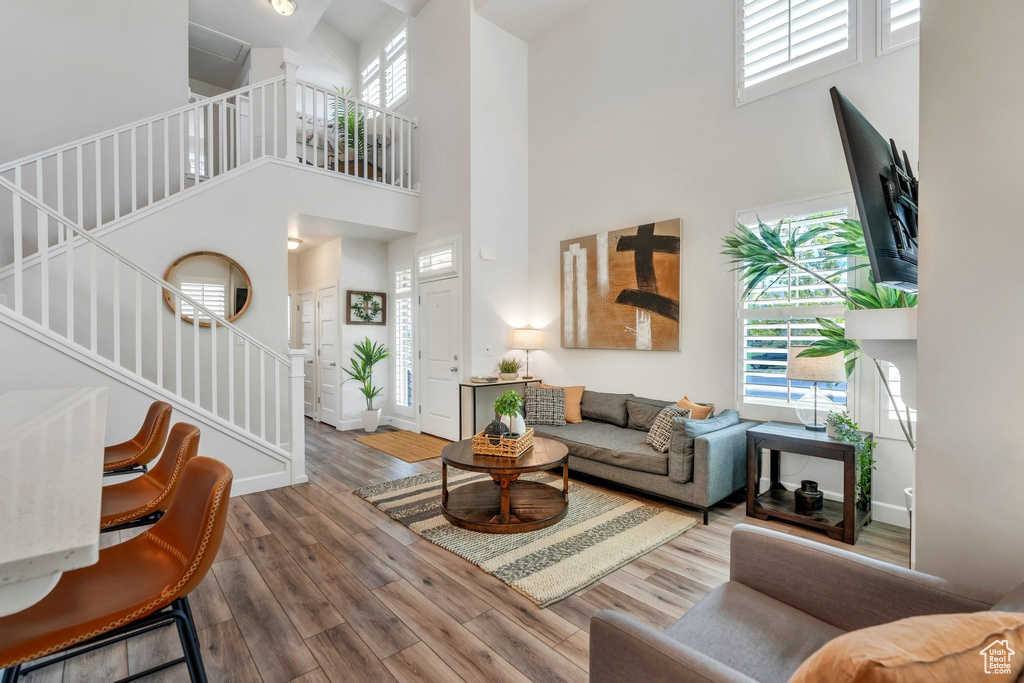 Living area with a high ceiling, stairs, wood finished floors, and baseboards