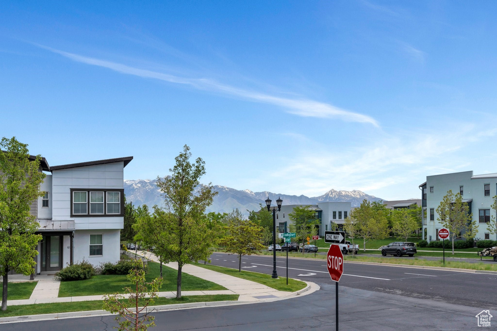 View of asphalt street with traffic signs, street lights, a mountain view, curbs, and sidewalks