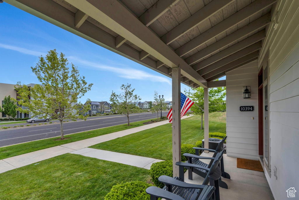 View of green lawn with a porch, central AC, and a residential view