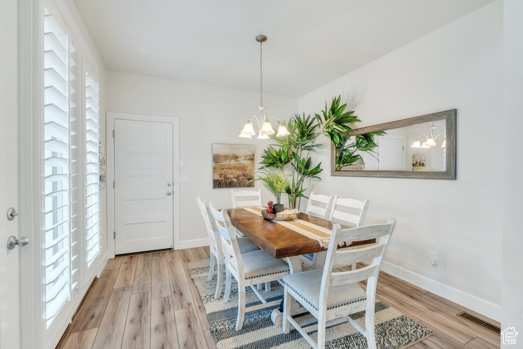 Dining space featuring plenty of natural light, light wood-style flooring, a chandelier, and baseboards