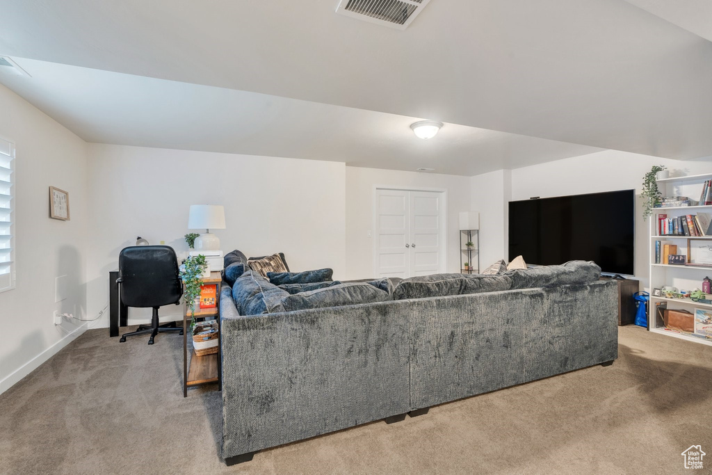 Carpeted living room featuring a desk and baseboards