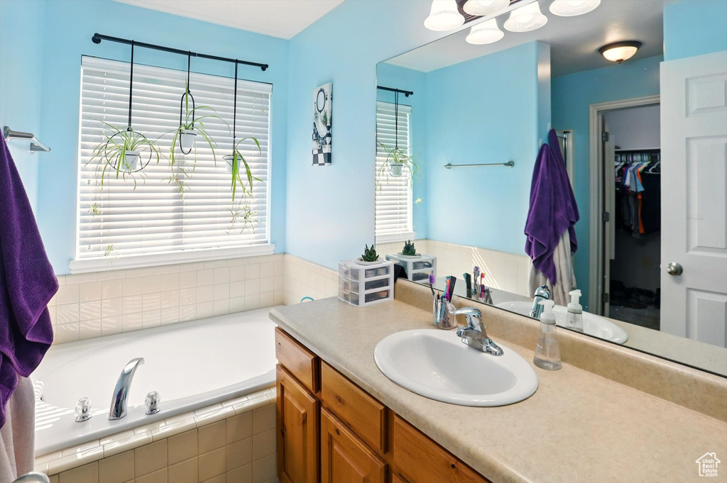 Full bathroom featuring vanity, a garden tub, and a spacious closet