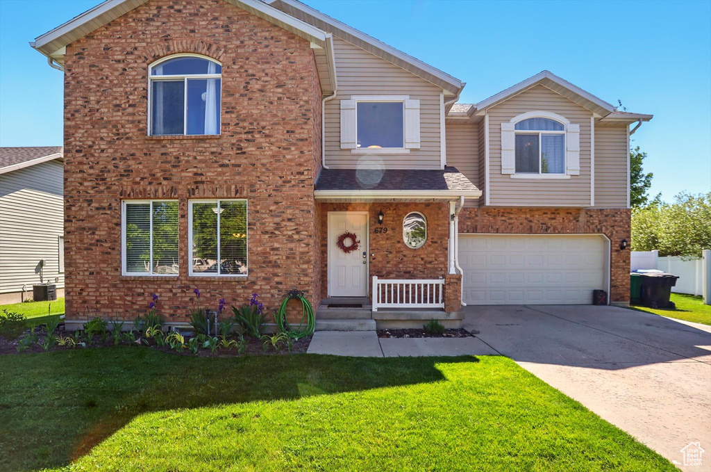 View of front of home with brick siding, concrete driveway, a front yard, and a garage