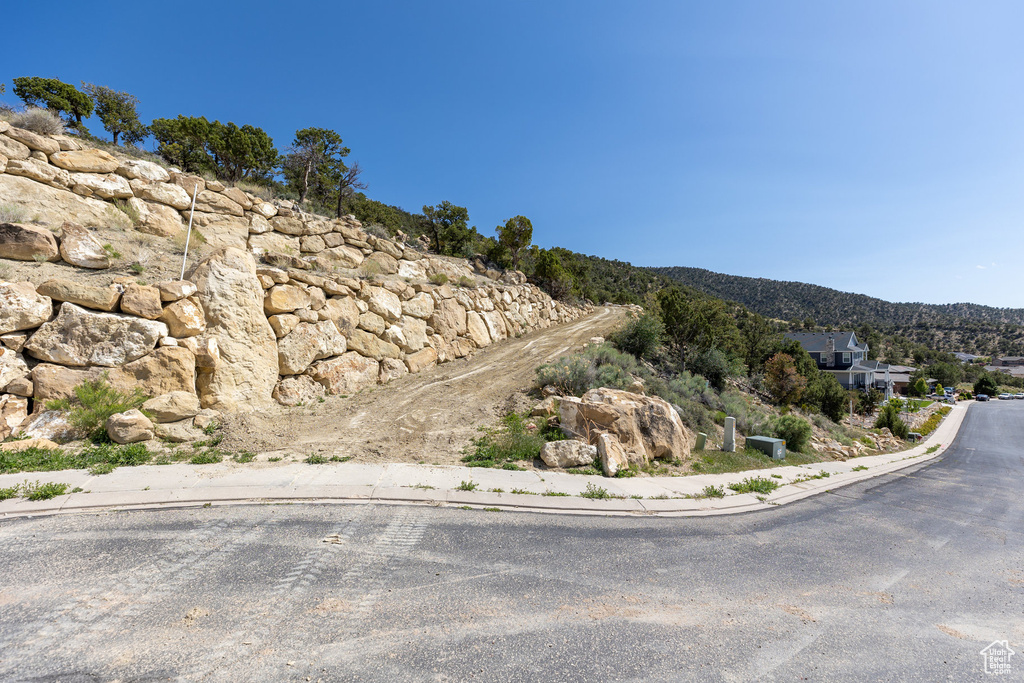 View of asphalt road featuring sidewalks, a mountain view, and curbs