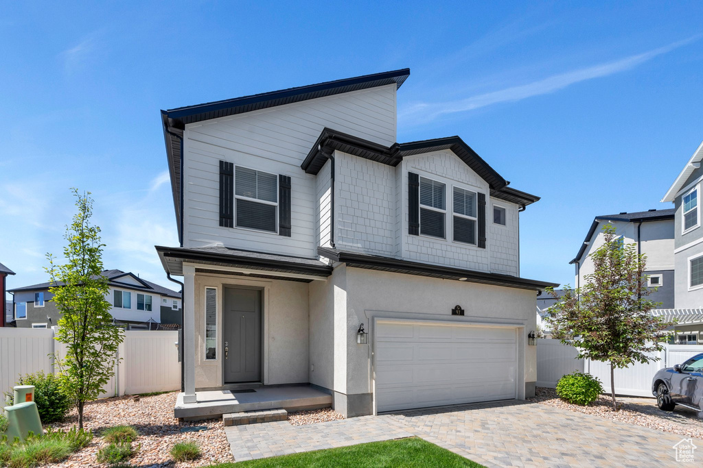 View of front of property featuring a garage and decorative driveway