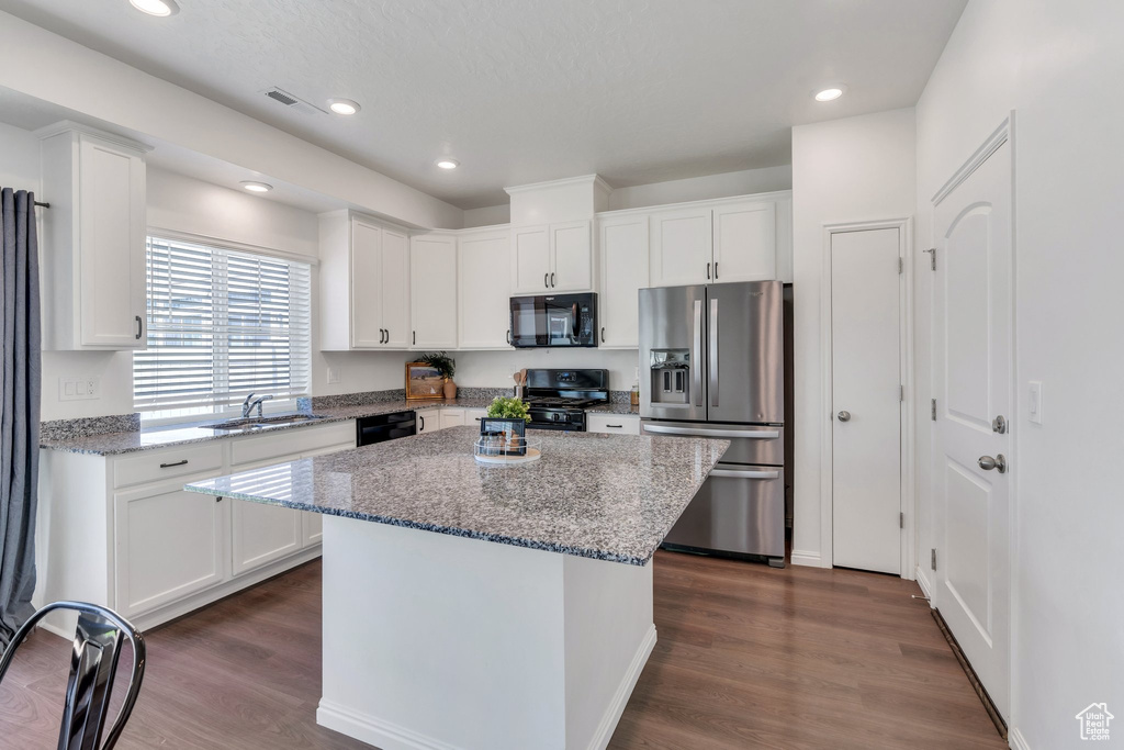 Kitchen featuring black appliances, a sink, white cabinetry, a kitchen island, and dark wood-style flooring