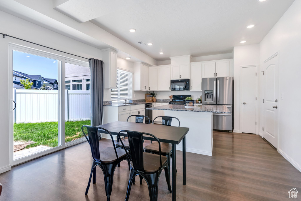 Kitchen with black appliances, a kitchen island, dark wood finished floors, white cabinets, and a sink