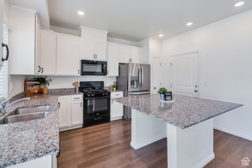 Kitchen featuring black appliances, a sink, dark wood-style floors, a kitchen island, and white cabinets