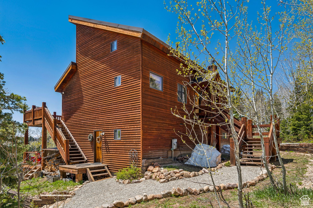 View of property exterior featuring stairs and a wooden deck