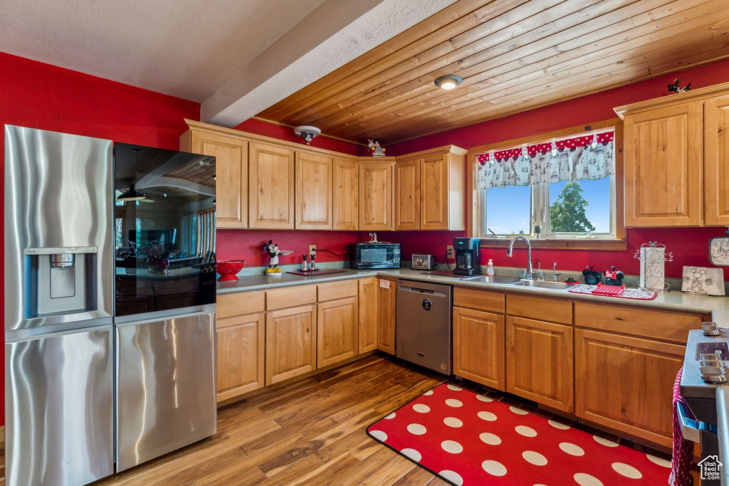 Kitchen featuring stainless steel appliances, a sink, wood finished floors, and light countertops