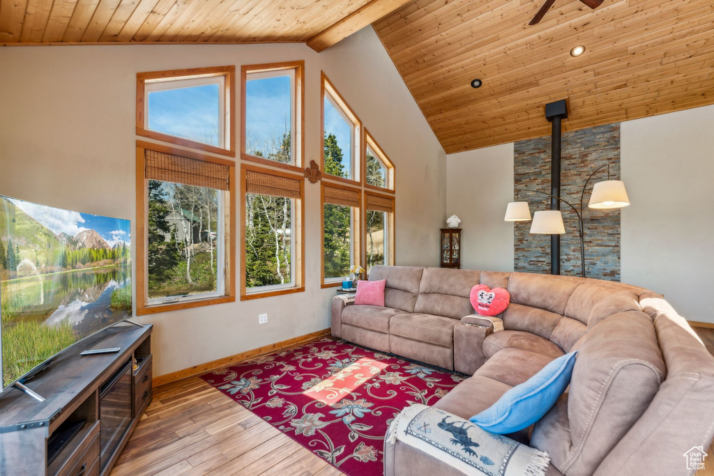 Living room featuring wooden ceiling with exposed beams, light wood-type flooring, high vaulted ceiling, baseboards, and ceiling fan