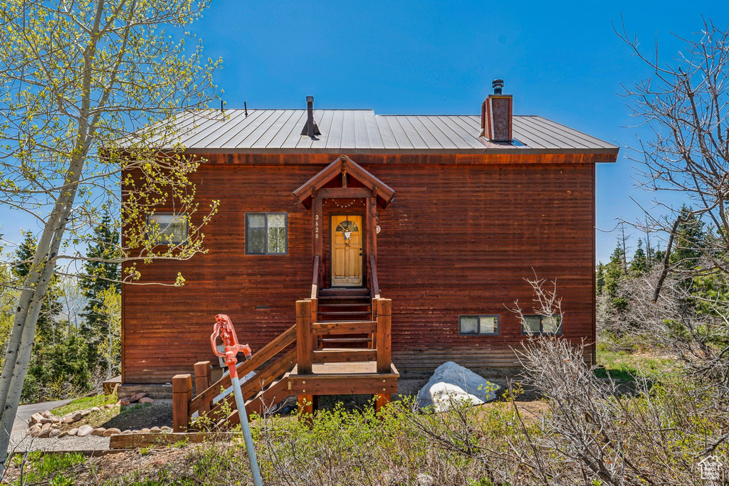 View of front of property with a chimney, a standing seam roof, and metal roof