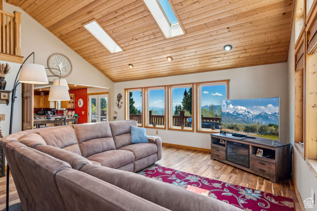Living room with a skylight, lofted ceiling, hardwood / wood-style floors, wooden ceiling, and baseboards