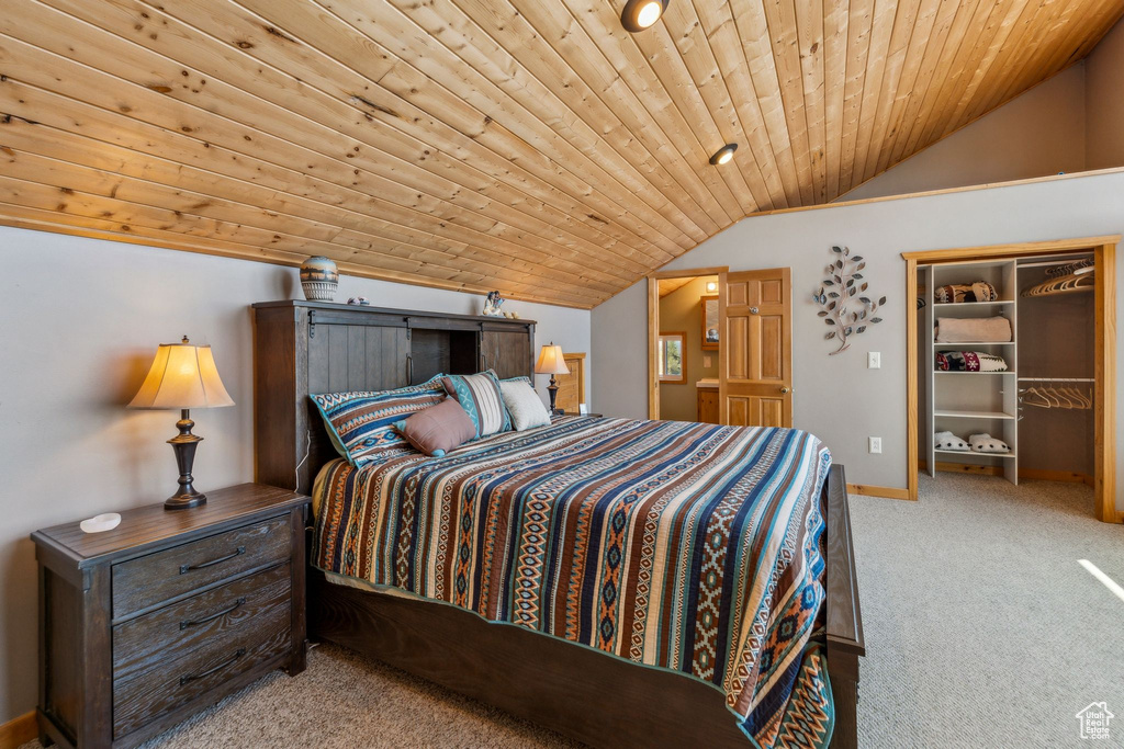 Carpeted bedroom with vaulted ceiling, wooden ceiling, baseboards, and a walk in closet