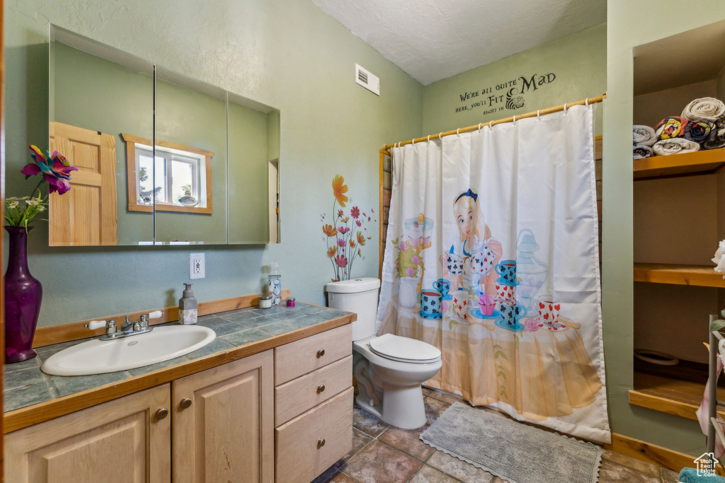 Full bathroom with vanity, toilet, and curtained shower