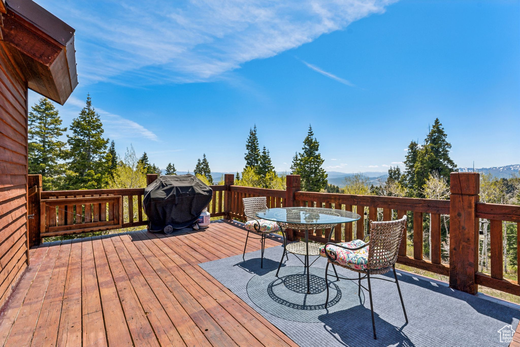 Deck featuring outdoor dining space, a mountain view, and a grill