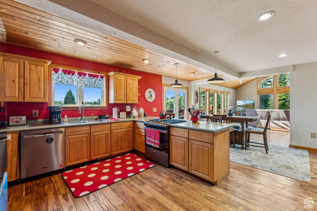 Kitchen featuring appliances with stainless steel finishes, a sink, a peninsula, recessed lighting, and light wood-style flooring