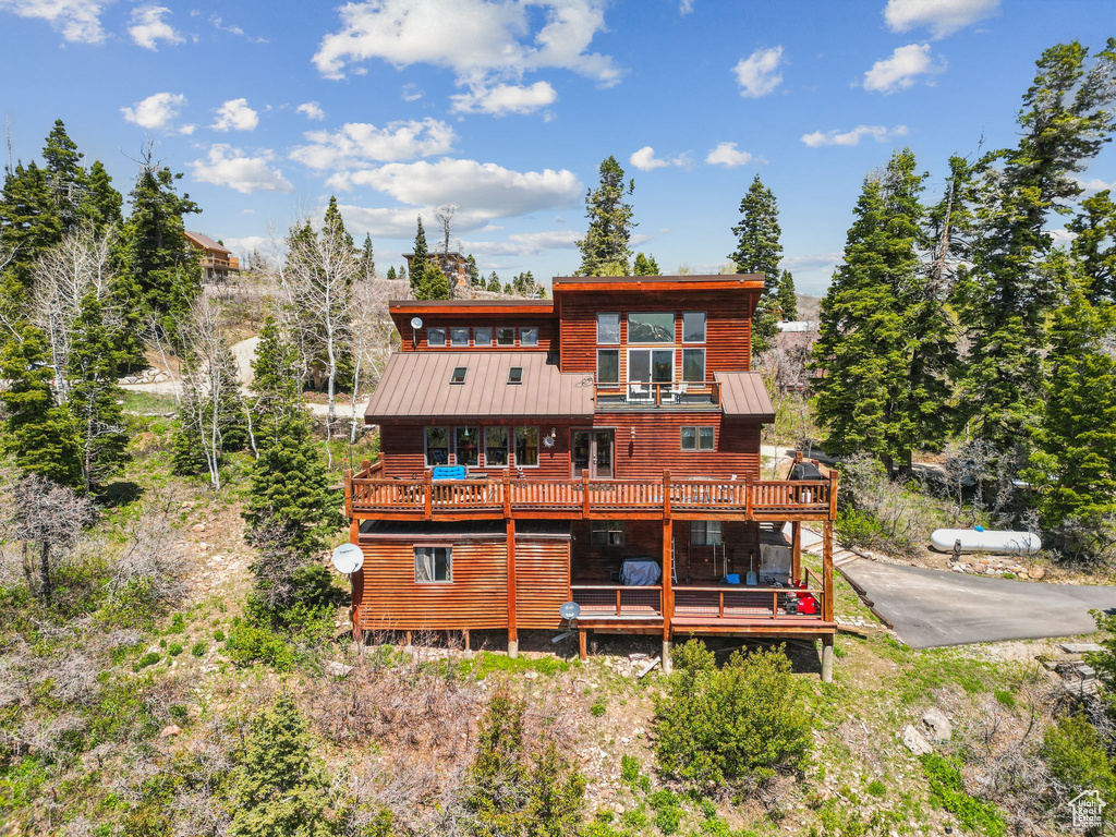 Rear view of property with a standing seam roof, a balcony, metal roof, and a wooden deck