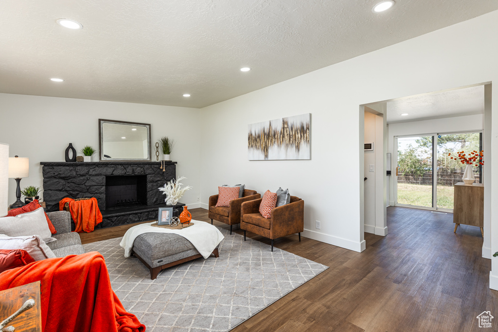 Living area featuring recessed lighting, baseboards, wood finished floors, and a stone fireplace