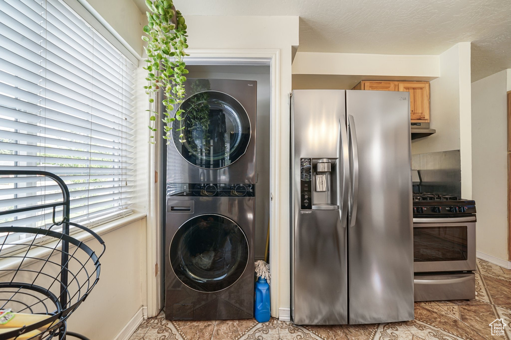 Washroom featuring stacked washing machine and dryer and baseboards
