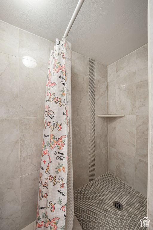 Full bath featuring a stall shower and a textured ceiling