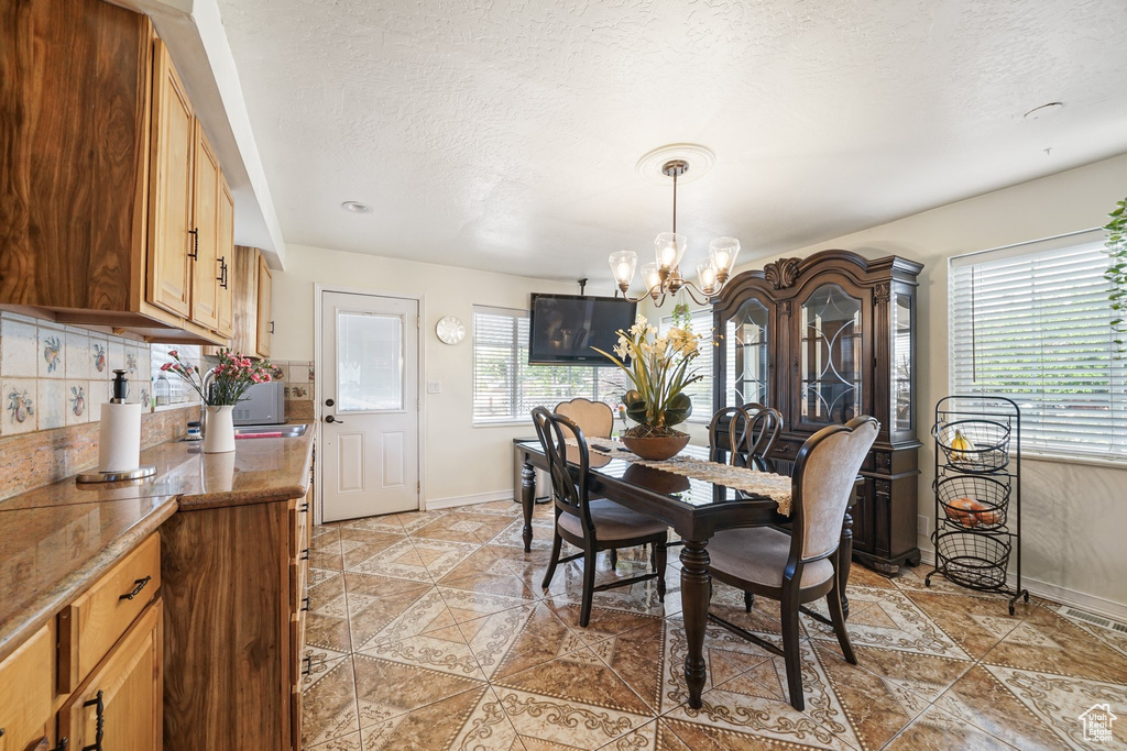 Dining space with a chandelier, baseboards, light tile patterned floors, and a textured ceiling