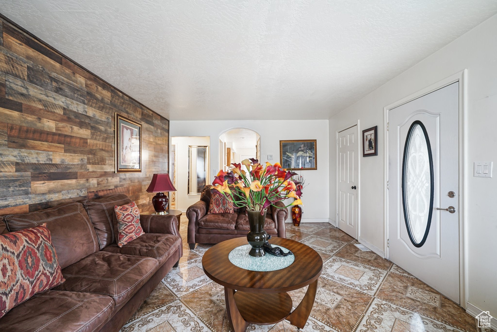 Foyer with wooden walls, an accent wall, arched walkways, baseboards, and light stone finish flooring