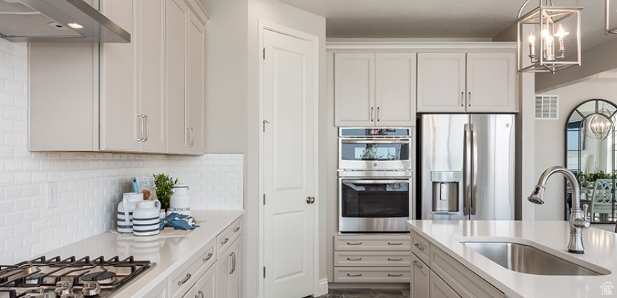 Kitchen with appliances with stainless steel finishes, a sink, a chandelier, and light countertops