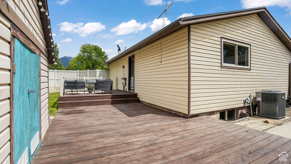 Wooden deck featuring central AC unit, an outdoor living space, and a mountain view