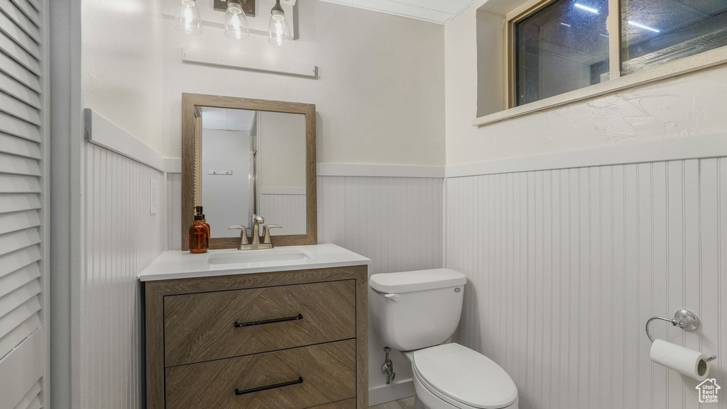 Bathroom featuring toilet, a wainscoted wall, and vanity