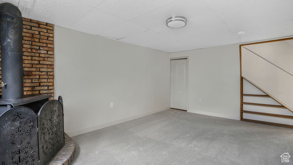 Unfurnished living room with carpet, a wood stove, and baseboards