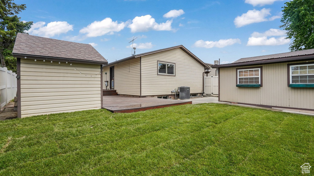 Back of property featuring an outbuilding, central AC, a wooden deck, and roof with shingles