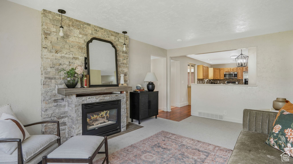 Living area featuring a stone fireplace, light colored carpet, and baseboards
